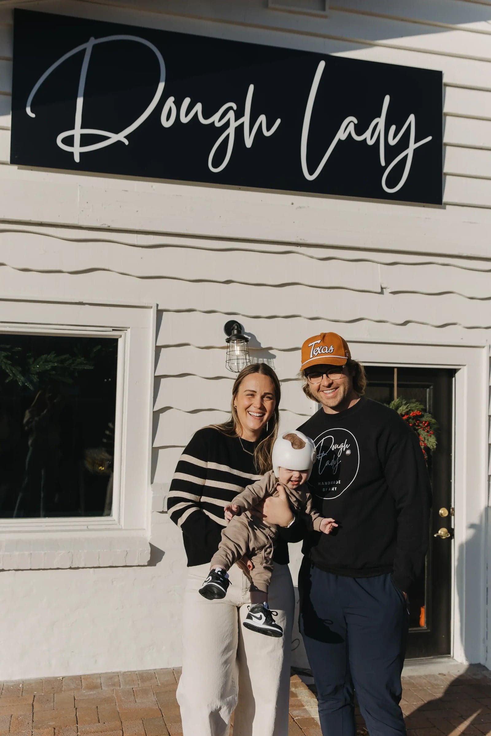 Amy and Eric with their baby in front of the Dough Lady storefront